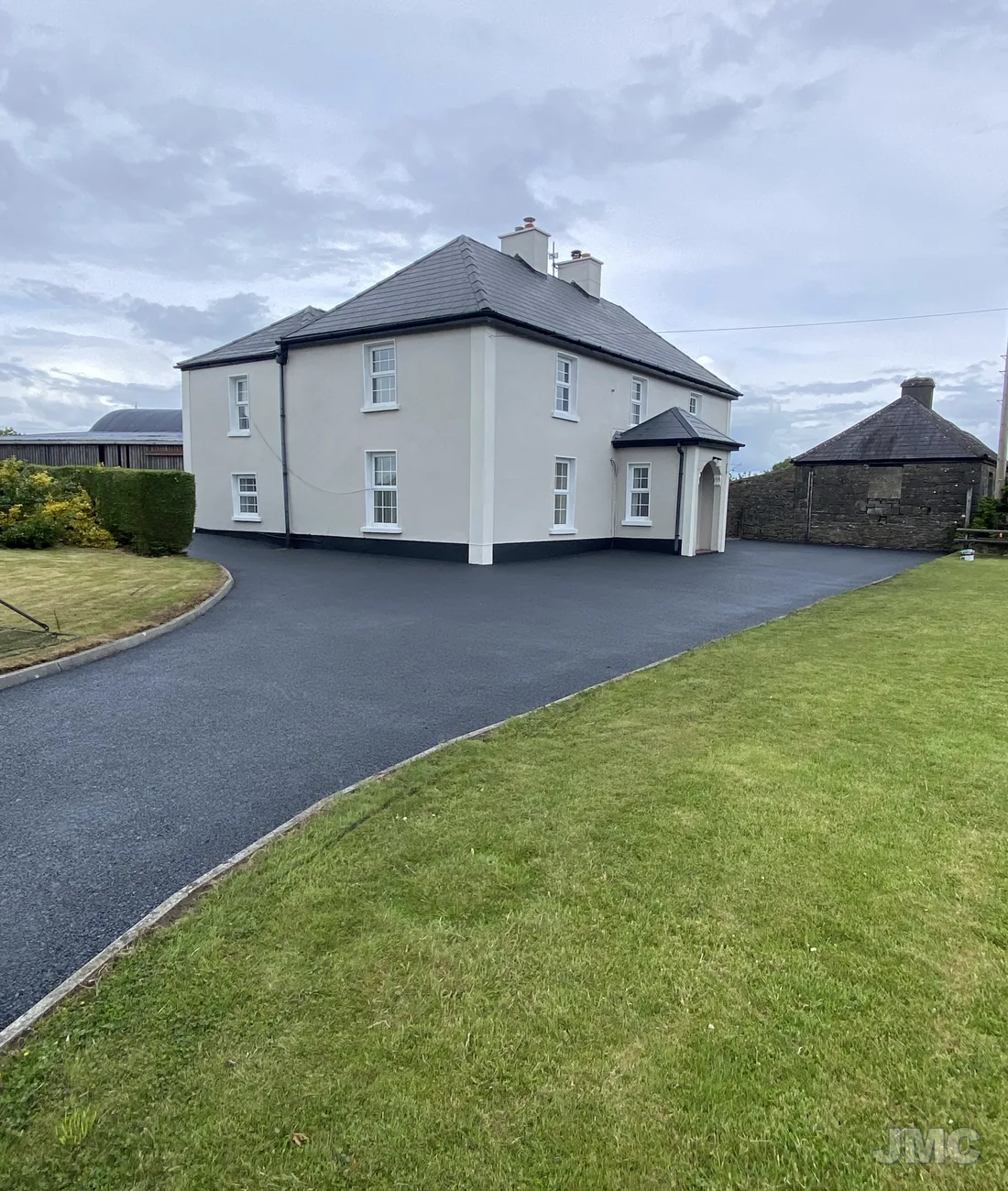 A white two-storey house with a freshly cleaned tarmac drive